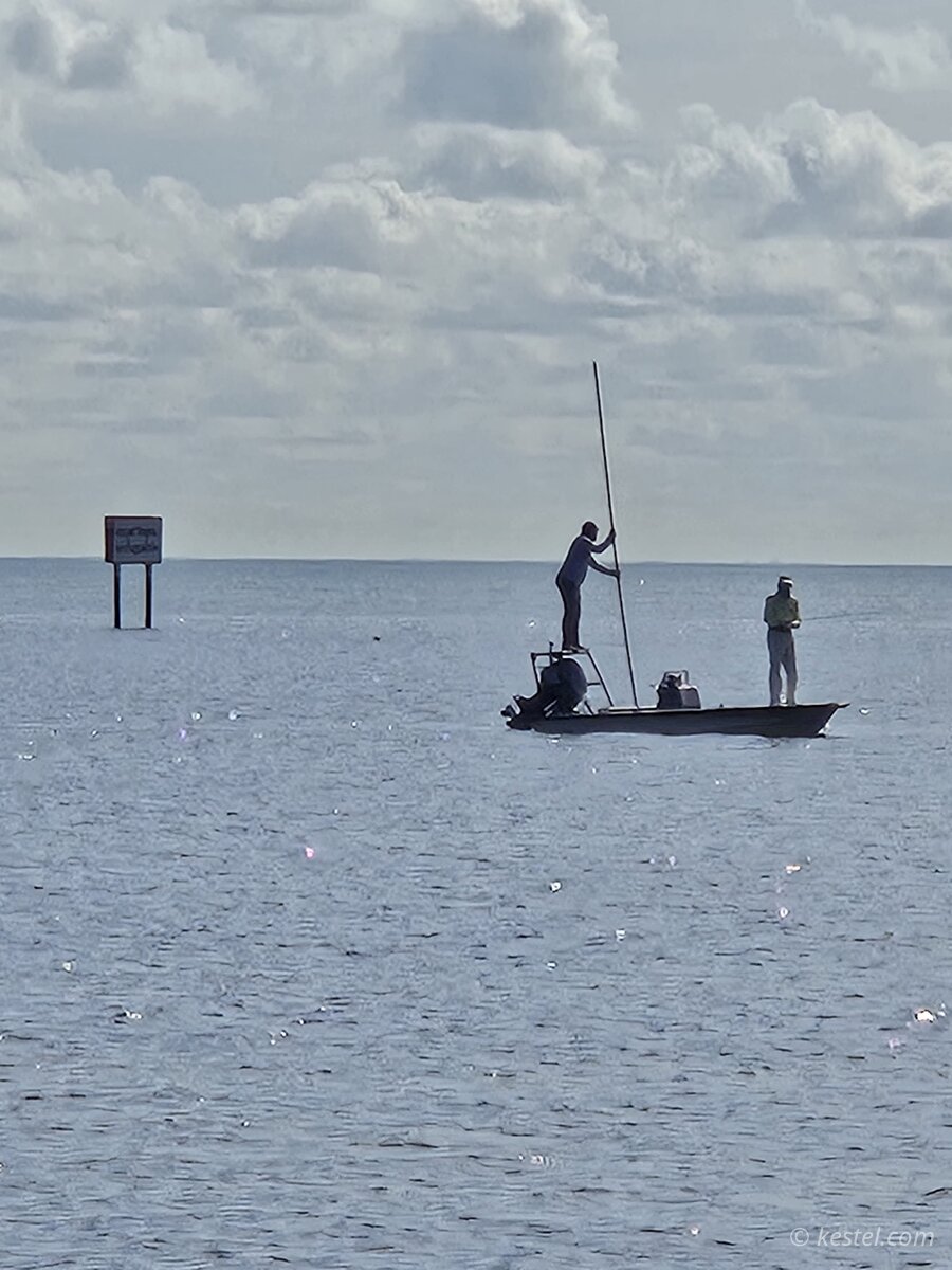 Flats fishing boat with push pole on calm bay at dusk