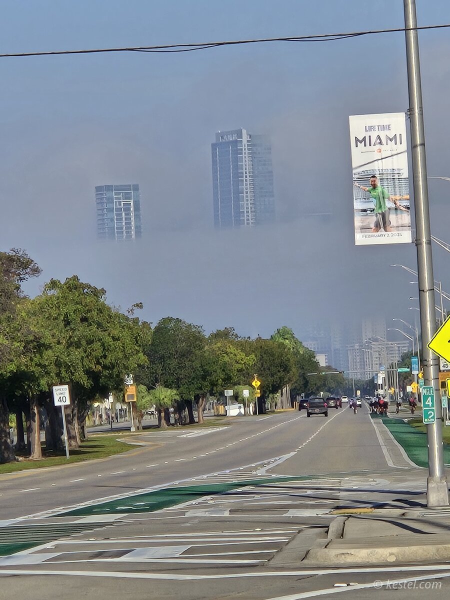 Cyclists crossing a bridge with Miami skyline in fog