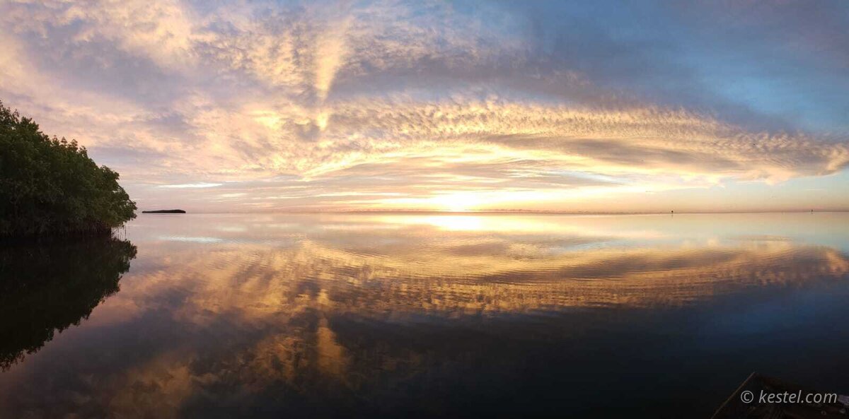 Arching clouds at sunrise over water