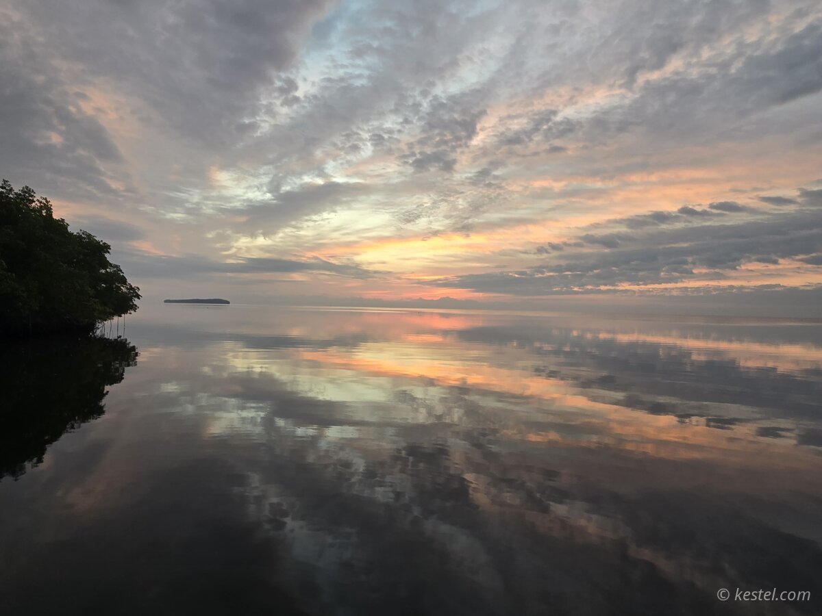 Pastel sunrise reflected in calm bay water