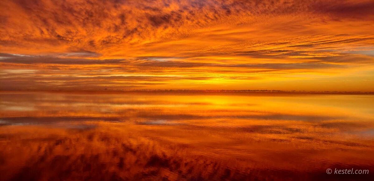 Orange sunrise mirrored in perfectly calm water