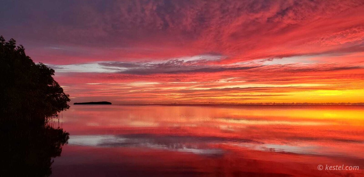 Pink sunrise reflected in calm bay water