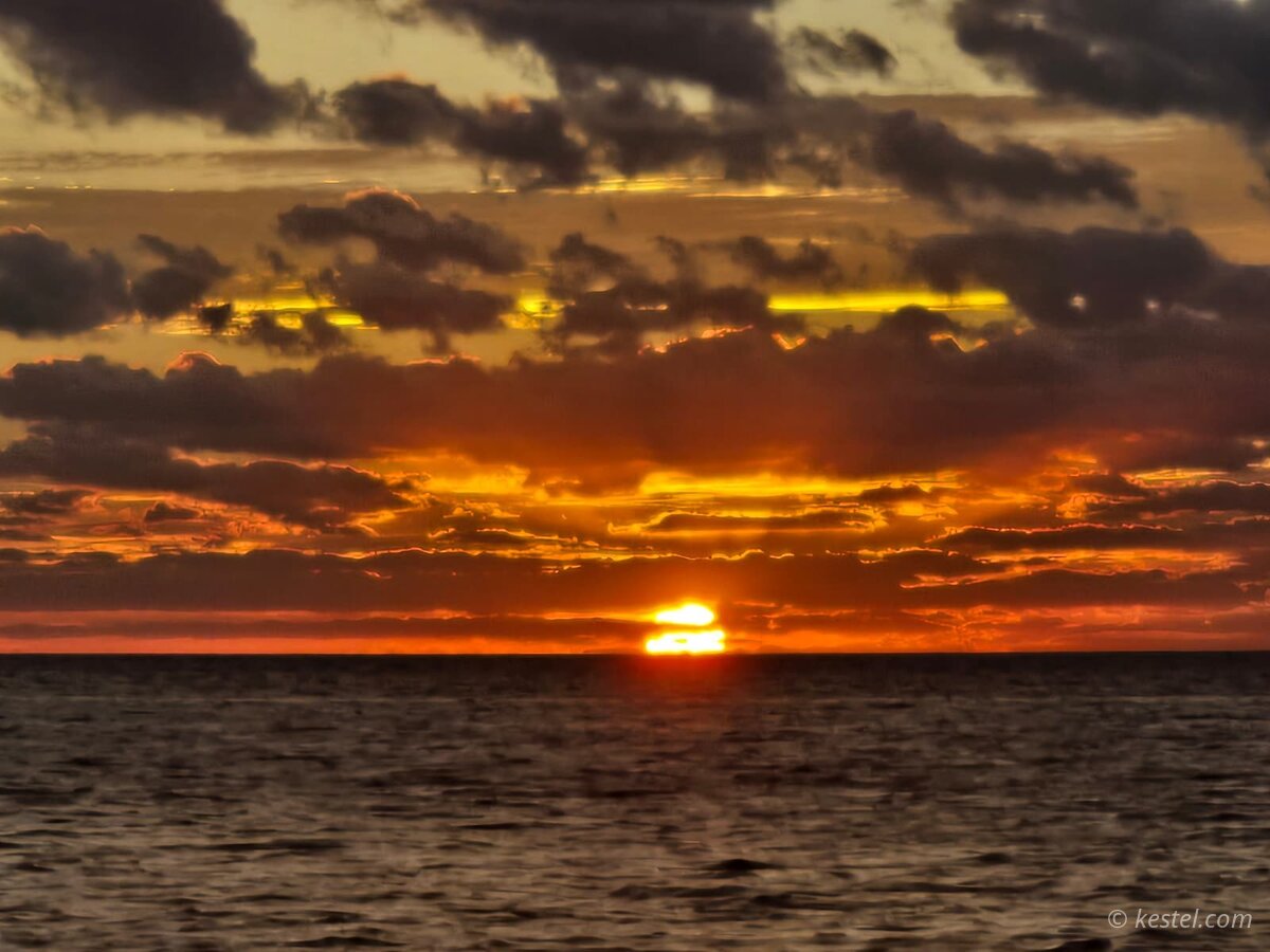 Optical mirage creating double sun effect at sunset over open water