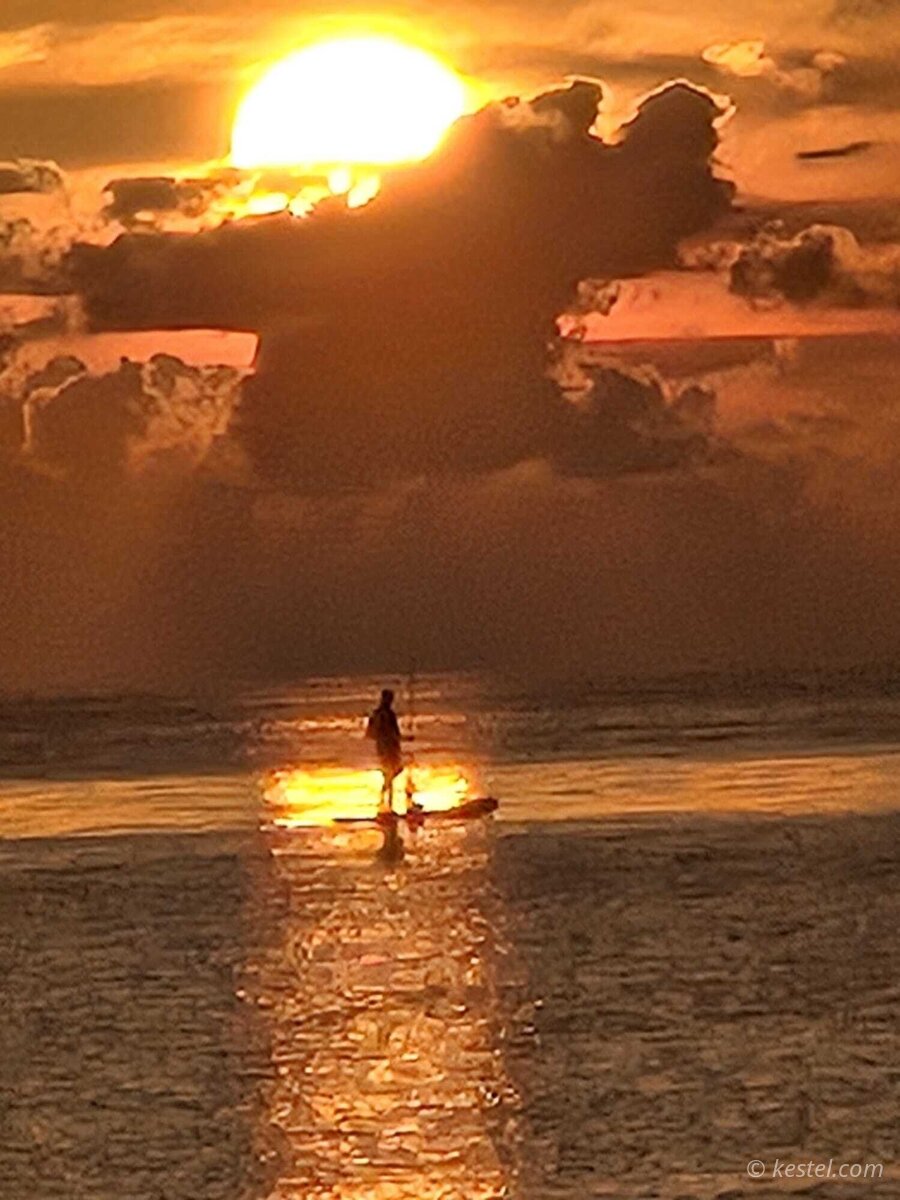 Sun setting through dramatic clouds over open water