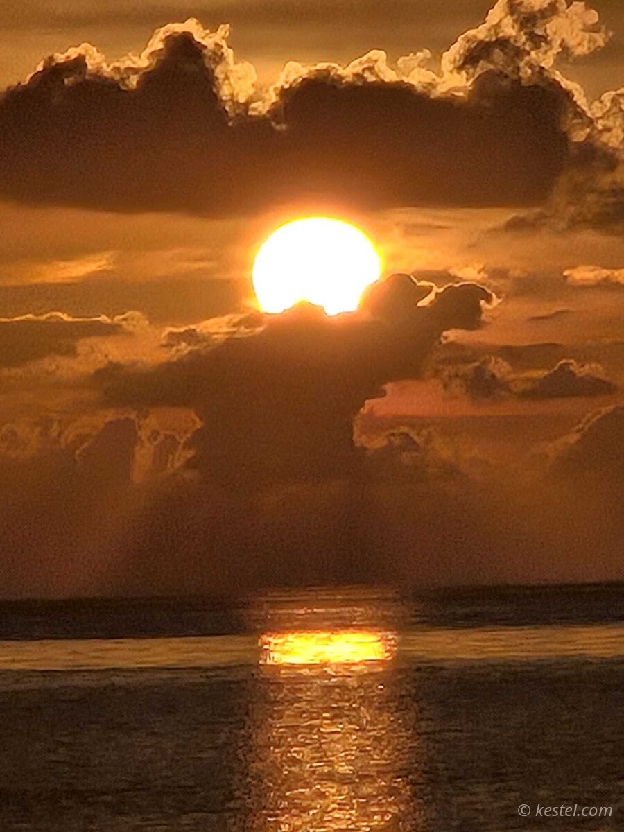 Golden sunset with layered clouds over open water