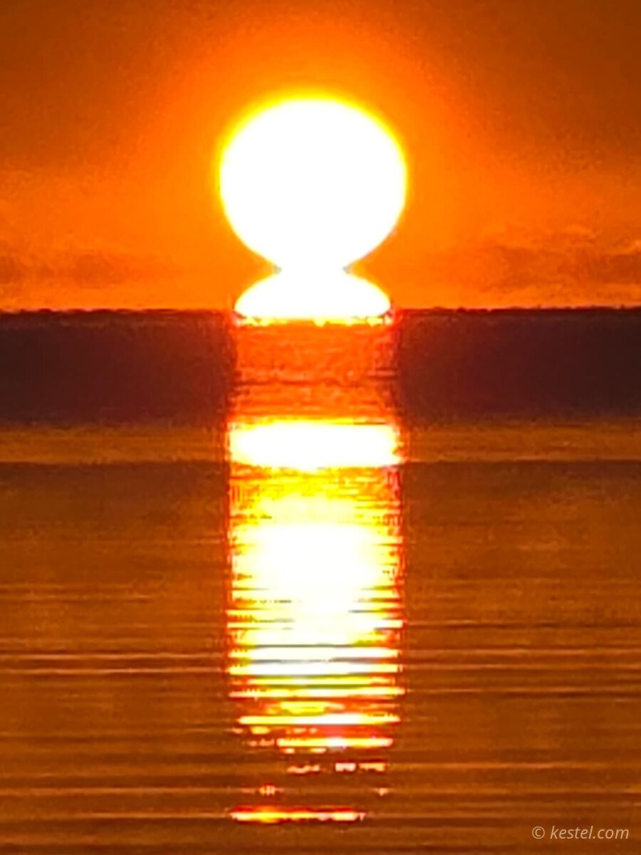 Paddleboarder silhouetted against a dramatic sunset