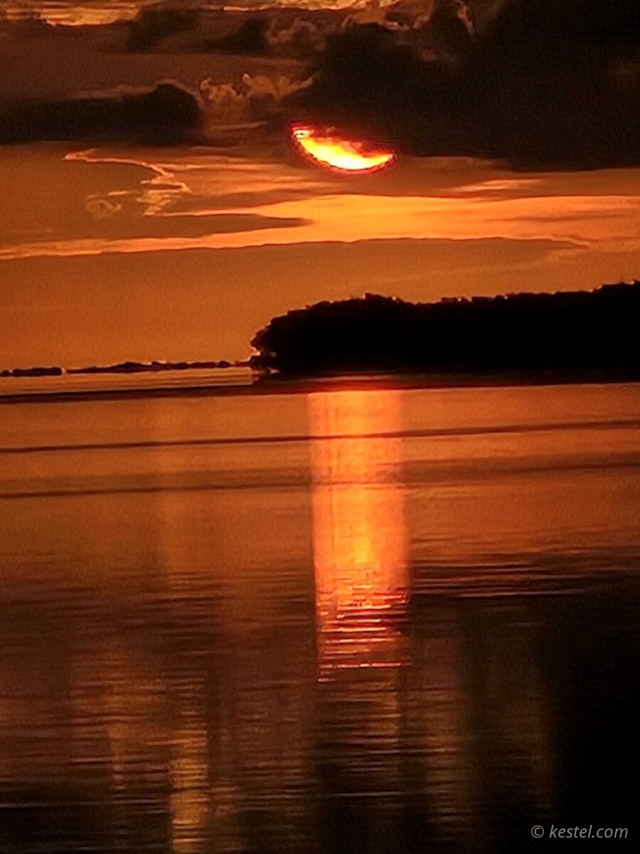 Crescent sun peeking through clouds at Virginia Key sunrise