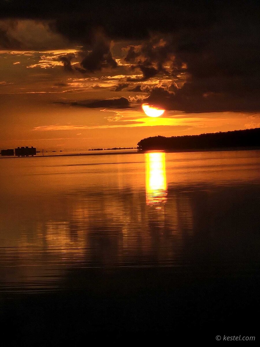 Half sun rising over island silhouette at Virginia Key