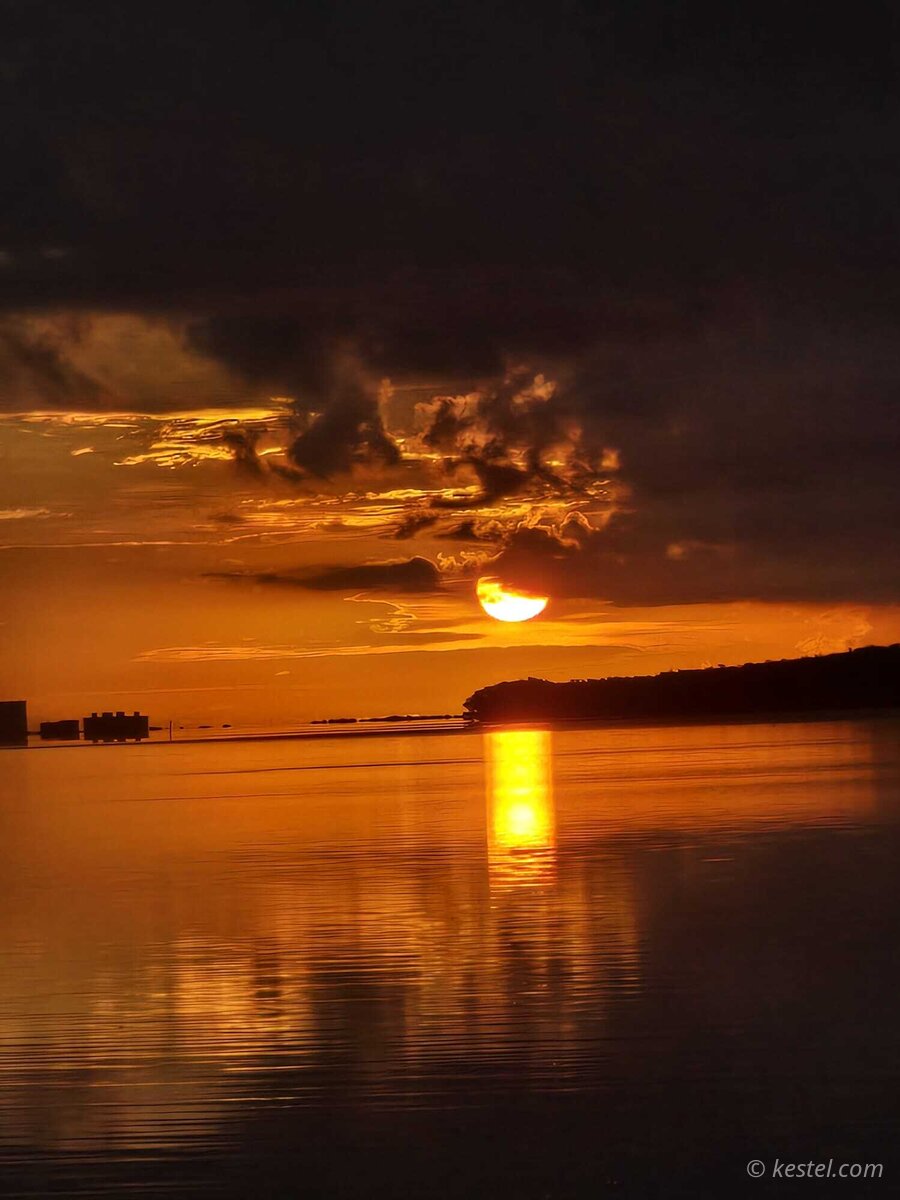 Half sun reflected in calm bay water at Virginia Key